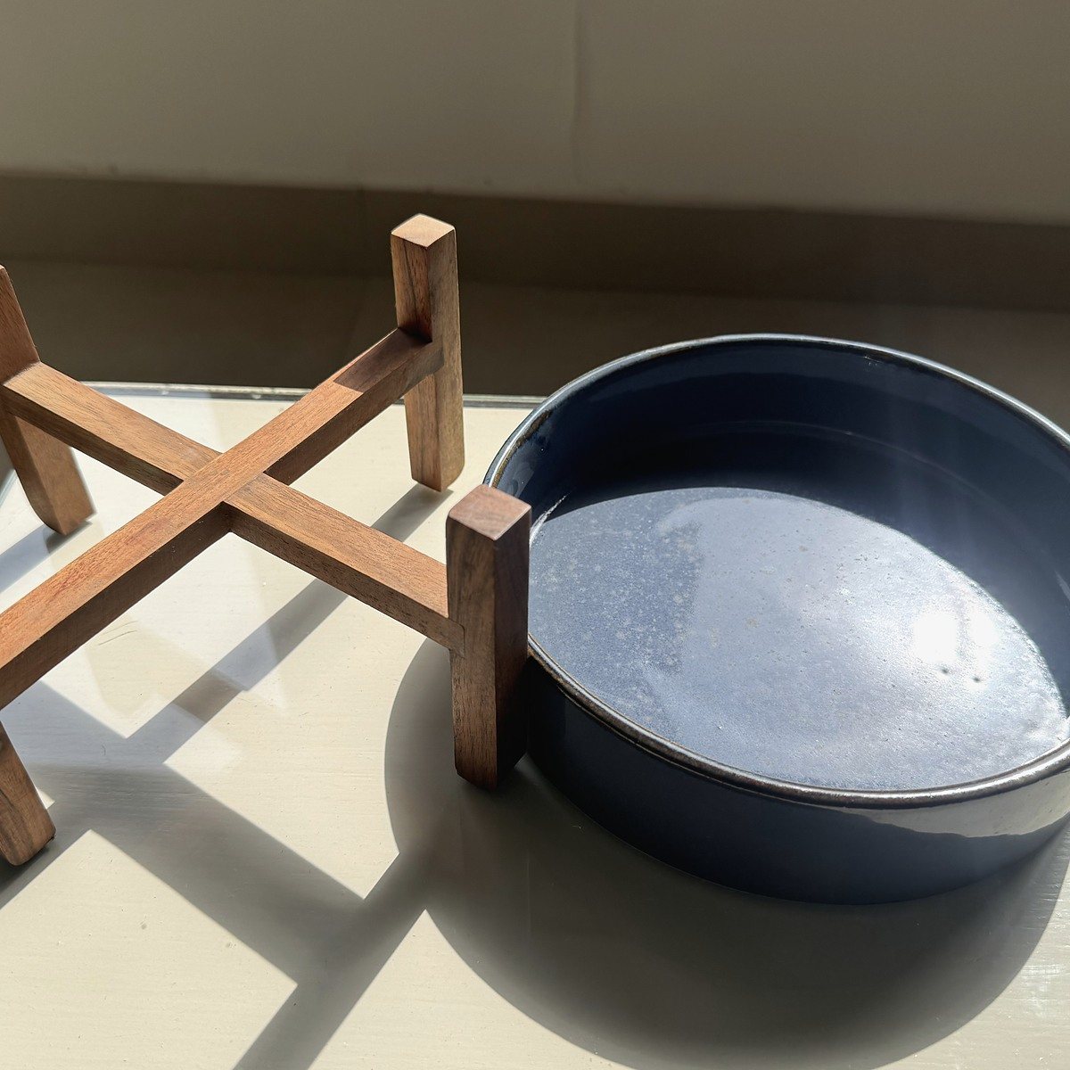 Wide blue-green ceramic bowl on a small wooden stand