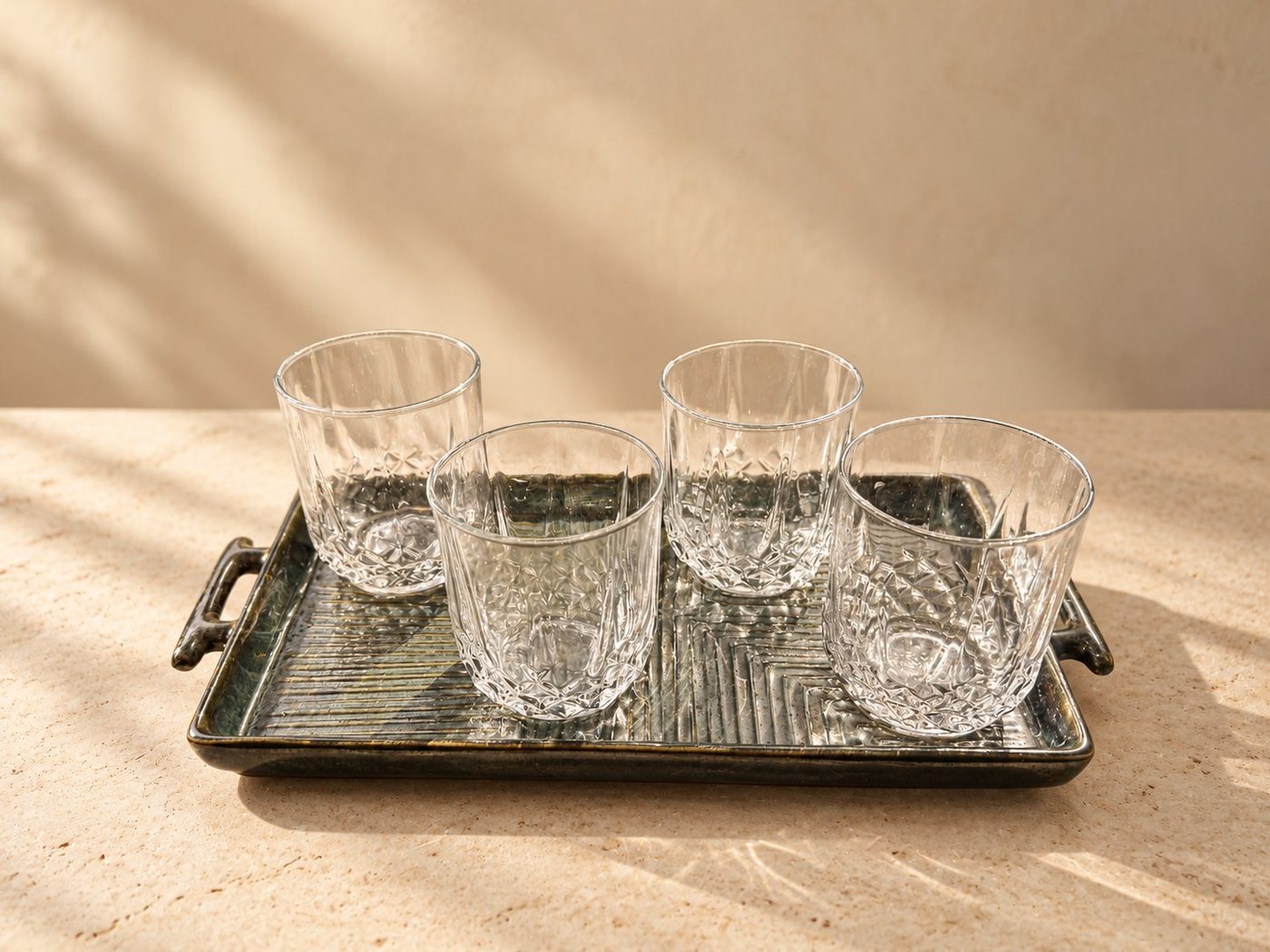 Four clear glasses presented on a charcoal ceramic tray