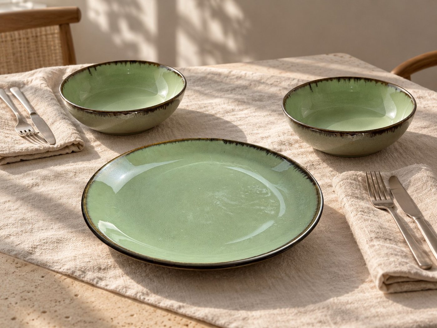 Sage green Bone & Kiln ceramics arranged on a softly lit dining table